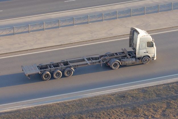 Truck with an empty long trailer without cargo driving on the highway top above view