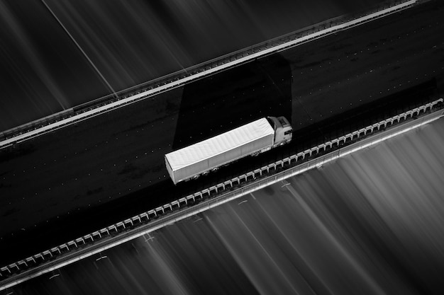 Грузовик с белым прицепом на темном асфальте черно-белое фото