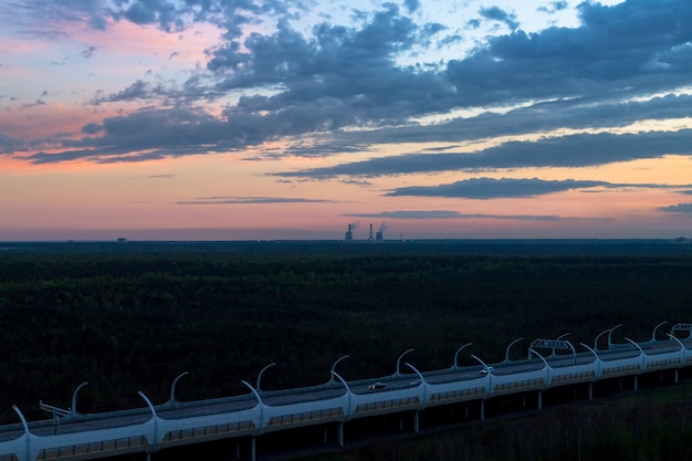 Trucks and cars driving on the highway turning towards the horizon in an autumn, summer landscape with pastel, amazing clouds in the sky. Copy space