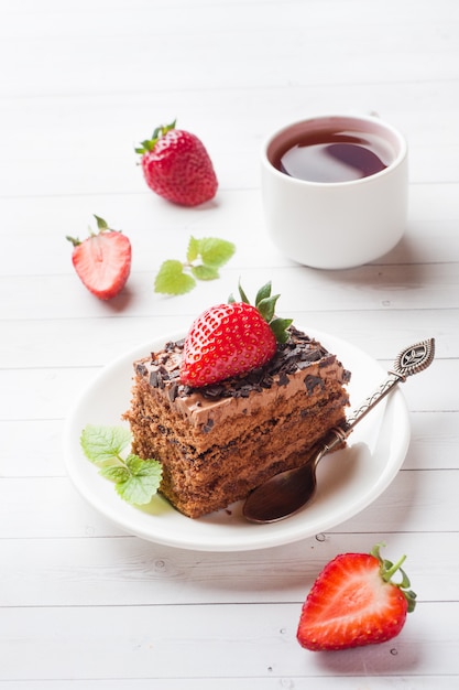 Трюфельный торт с шоколадом и клубникой и мятой на белом деревянном столе. выборочный фокус.