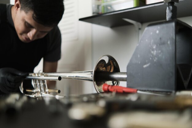 Trumpet on repair stand and a man working on it