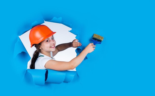 Photo trust me i am an expert kid wear helmet on construction site teen girl painter with painting brush tool child on repairing work concept of renovation in workshop busy professional carpenter