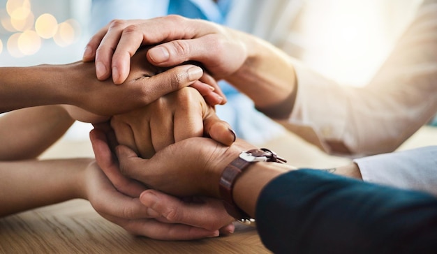 Trust and support Cropped shot of a group of unrecognizable businesspeople sitting in the boardroom with their hands in a huddle