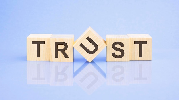 Trust word is written on wooden cubes closeup bright blue background white surface table