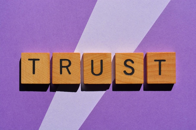trust word in wooden alphabet letters isolated on purple background