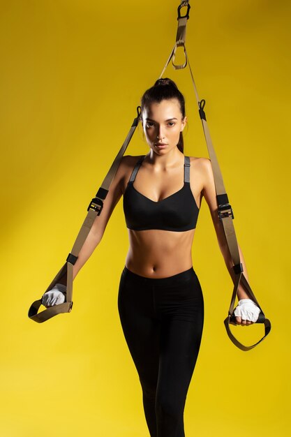 Trx exercises young sporty woman in sportswear doing push ups with trx fitness straps against