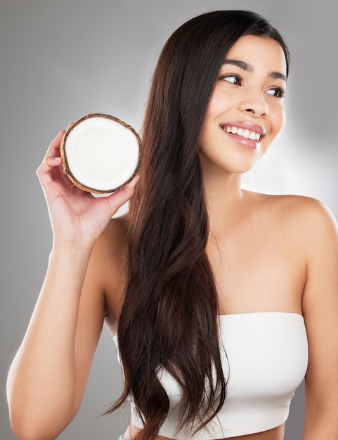 Trying new treatments. Studio shot of a beautiful young woman posing with a coconut against a grey background.