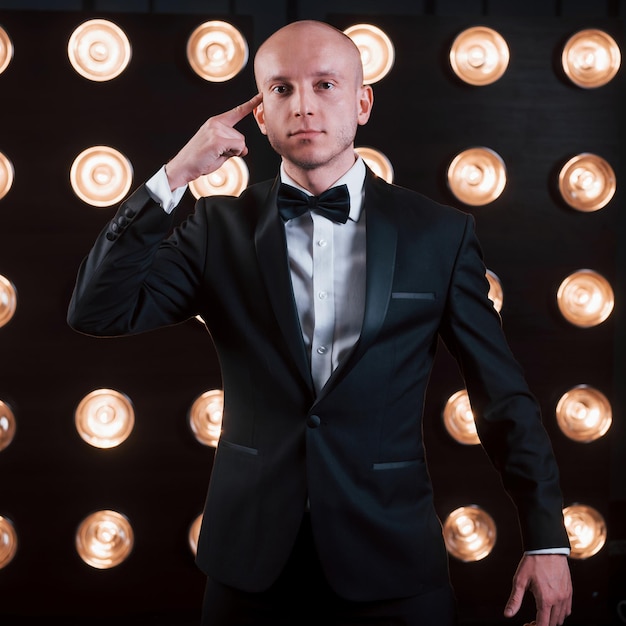 Photo trying to read your mind magician in black suit standing in the room with special lighting at backstage