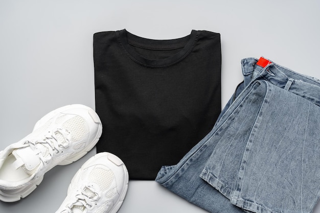 Tshirt jeans and white sneakers on gray background top view