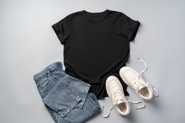 Tshirt jeans and white sneakers on gray background top view