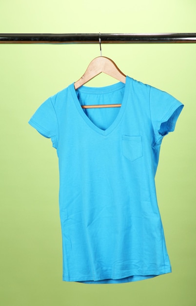 Tshirt on wooden hanger on green background