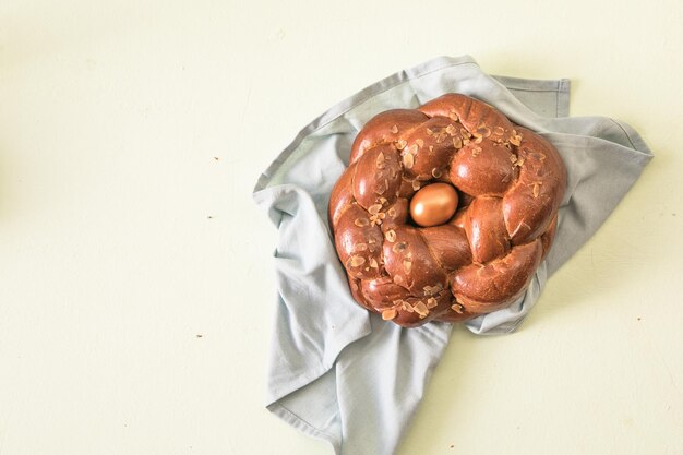 Tsoureki traditional baked Greek Easter sweet bread garnished with slivered almonds and decorated with a boiled red dyed egg in the middle