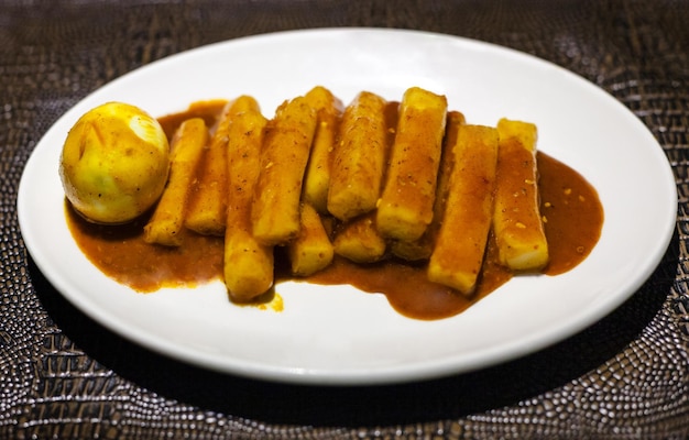 Tteok bokki-snack op witte plaat op leerbord