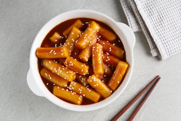 Tteokbokki met witte sesam in witte kom met grijze achtergrond