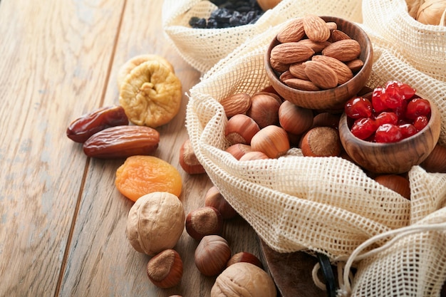 Tu Bishvat celebration concept Mix of dry fruits and nuts almonds hazelnuts walnuts apricots prunes cherries raisins dates apples figs over wooden table Jewish holiday new year of trees