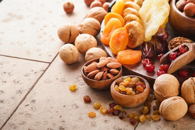 Tu Bishvat celebration concept Mix of dry fruits and nuts almonds hazelnuts walnuts apricots prunes cherries raisins dates apples figs over wooden table Jewish holiday new year of trees