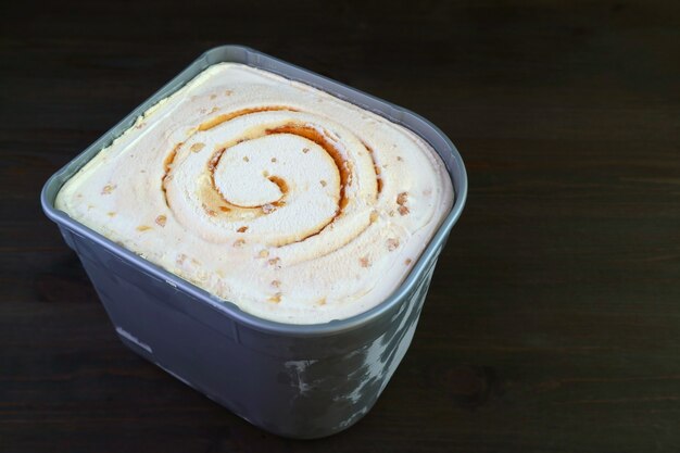 Tub of Tasty and Creamy Salted Caramel Macadamia Nut Ice Cream Isolated on Black Background