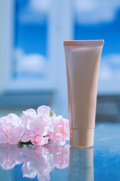 Tube of cream with flowers on a blue background