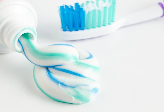 A tube of toothpaste and a toothbrush on white background closeup