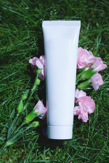 Tube of white cream on a background of green plants