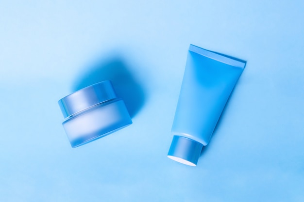 Tube with moisturizing mask blue and a jar of cream blue on a blue background