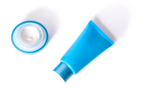 Tubo con maschera idratante blu e un barattolo di crema blu su sfondo bianco