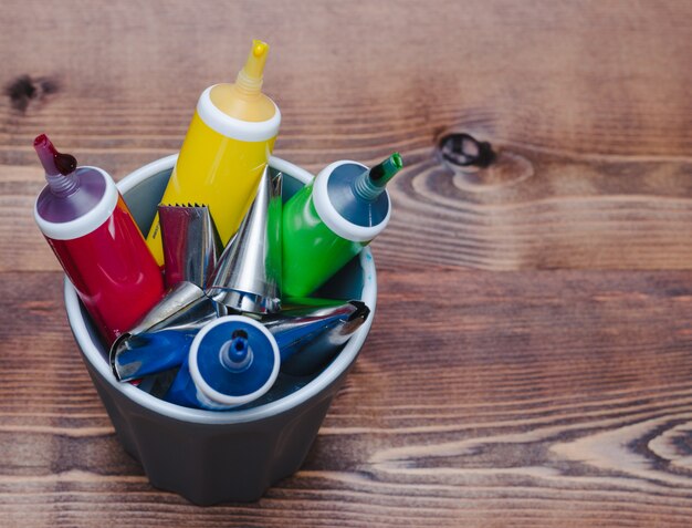 Tubes of colored paint on wooden background