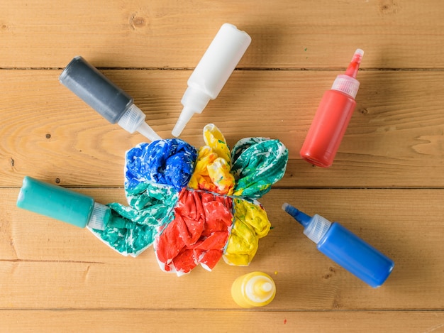 Tubes of fabric paint and a painted t-shirt on a wooden table.