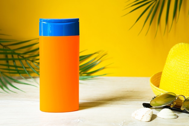 Tubes with mock up sunscreens on the table with yellow summer background. UV protection of the skin with an SPF filter, hair care-shampoo and conditioner. A safe tan on the beach, resort on the sea.