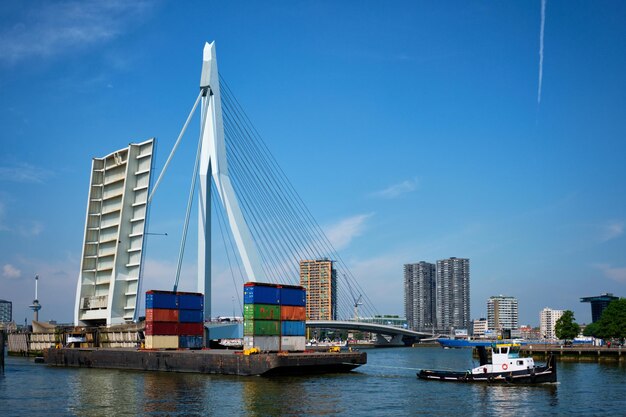 Tug boat towing barge with containers under open bascule part of Erasmusbrug bridge