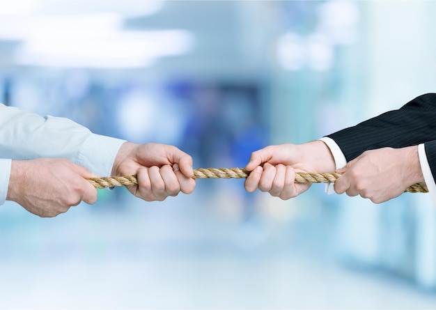 Tug war, two businessman pulling a rope in opposite directions