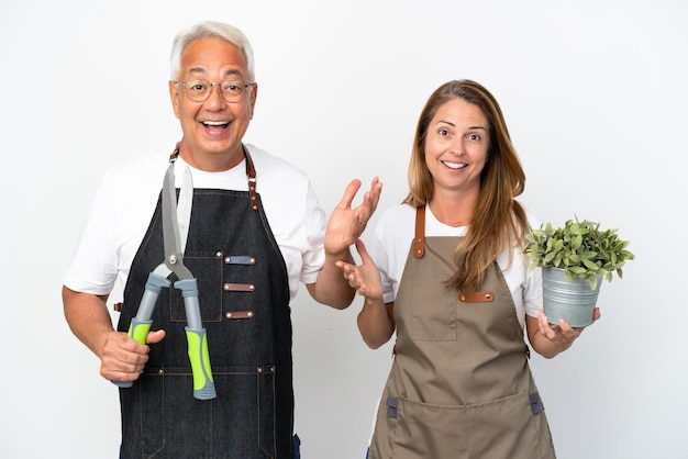 Tuinders van middelbare leeftijd met een plant en een schaar geïsoleerd op een witte achtergrond met verrassing en geschokte gezichtsuitdrukking