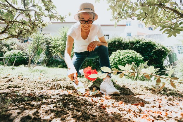 Tuinieren en mensen concept - gelukkige senior vrouw die bloemen plant in de zomertuin