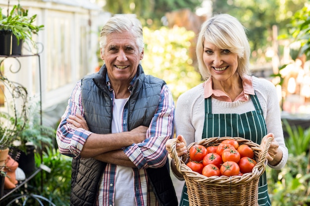 Tuinlieden met tomatenmand buiten serre