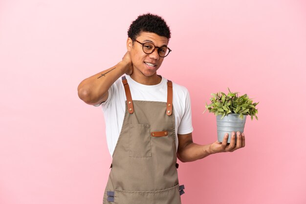 Tuinman afrikaanse man met een plant geïsoleerd op roze achtergrond lachen