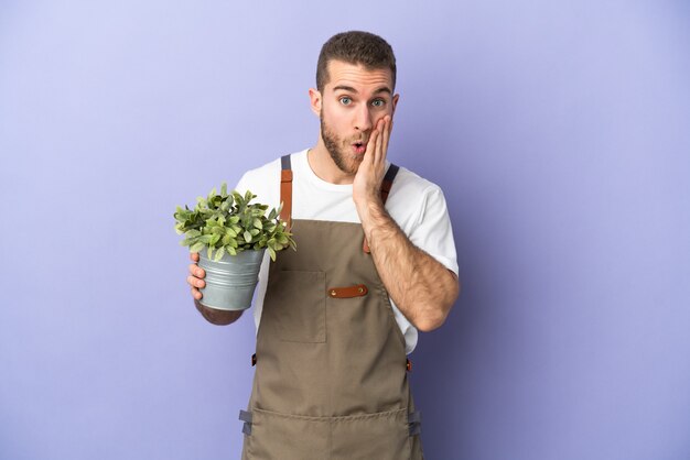 Tuinman blanke man met een plant geïsoleerd op geel met verbazing en geschokt gelaatsuitdrukking