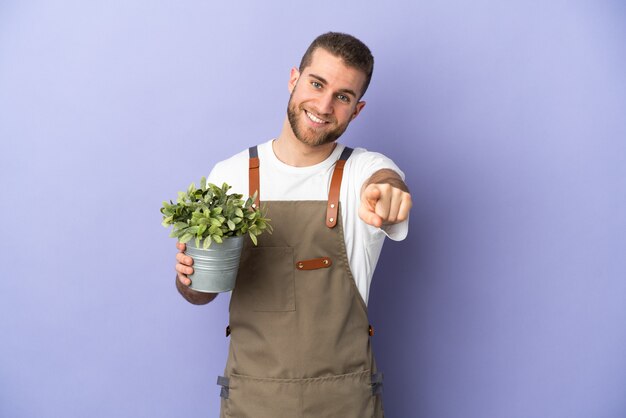 Tuinman blanke man met een plant geïsoleerd op geel wijzend front met gelukkige uitdrukking