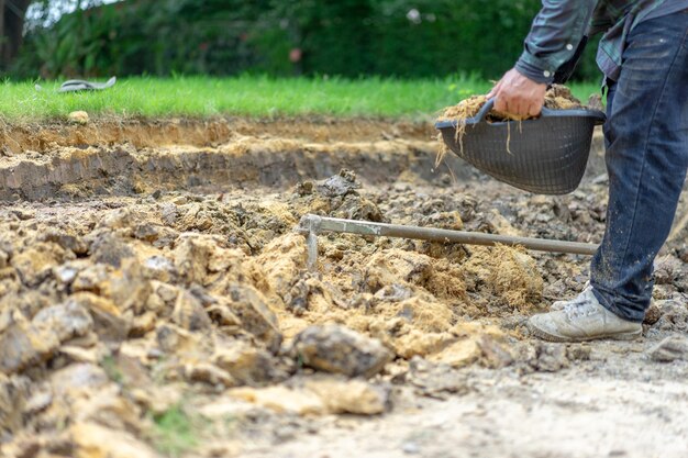 Tuinman graaft de grond met zijn uitrusting om te tuinieren en maakt land klaar voor plantage.