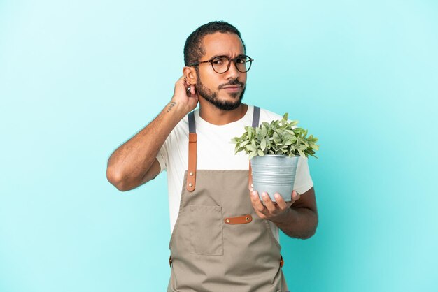 Tuinman Latijns-man met een plant geïsoleerd op blauwe achtergrond met twijfels