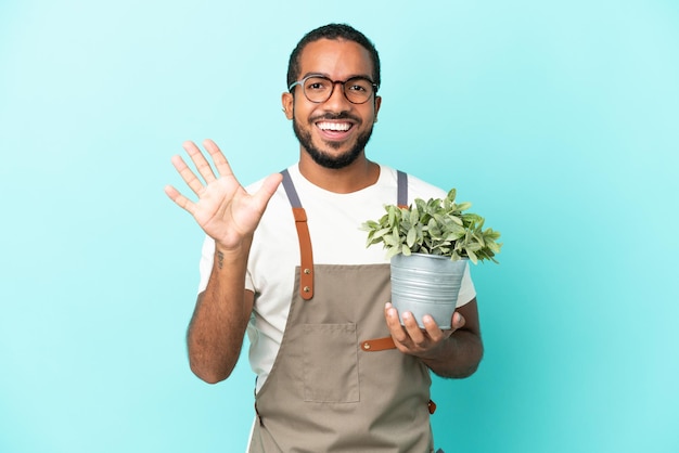 Tuinman Latijns-man met een plant geïsoleerd op blauwe achtergrond vijf tellen met vingers