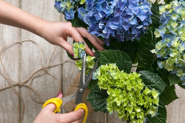 Tuinman maakt een boeket kasbloemen. De bloemist werkt in een kas met een paars boeket. Floristiek workshop, vaardigheid, decor, klein bedrijfsconcept