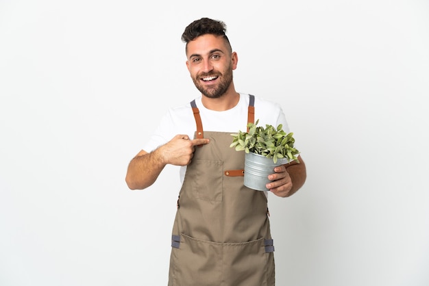 Tuinman man met een plant over geïsoleerde witte muur met verrassingsgelaatsuitdrukking