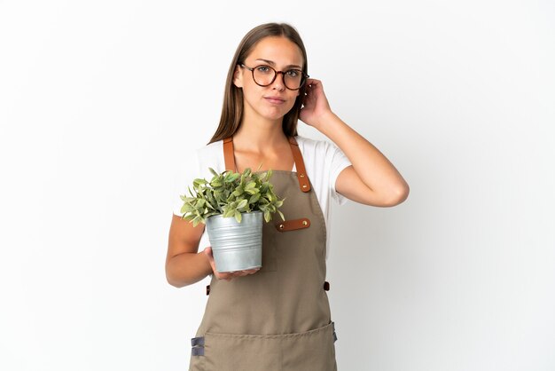 Tuinman meisje met een plant geïsoleerd met twijfels