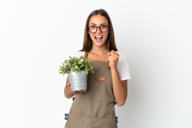 Tuinman meisje met een plant over geïsoleerde witte achtergrond een overwinning vieren in de winnaarspositie