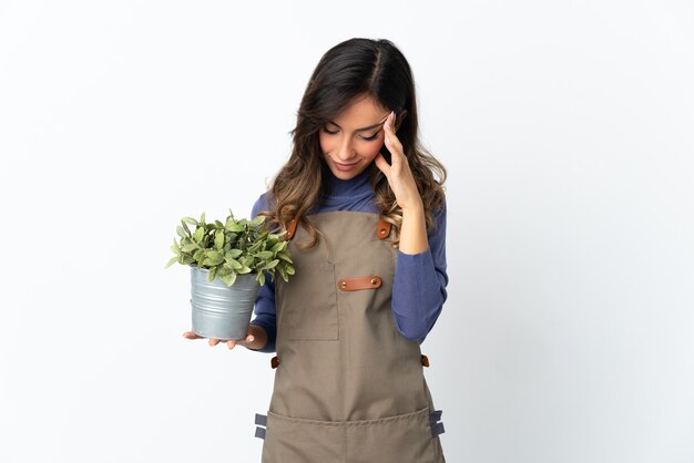 Tuinman meisje met een plant poseren geïsoleerd tegen de blinde muur