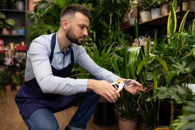 Tuinman verwijdert uitgebloeide planten met snoeischaar