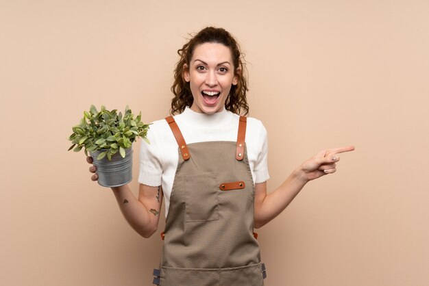 Tuinman vrouw met een plant verrast en wijzende vinger naar de kant