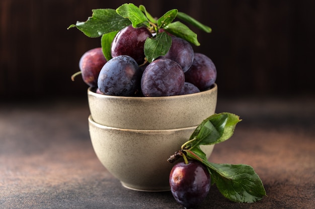 Tuinpruimen op tafel. sluit omhoog van verse pruimen met bladeren. herfstoogst van pruimen.