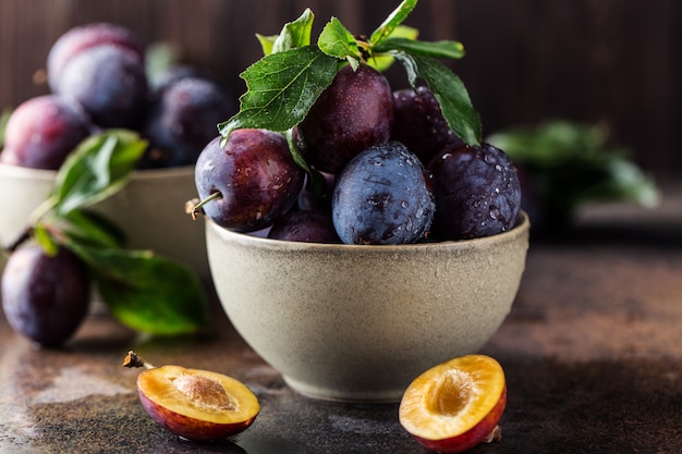 Tuinpruimen op tafel. Sluit omhoog van verse pruimen met bladeren. Herfstoogst van pruimen.