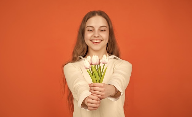 Photo tulip flowers in hands of happy child on orange background selective focus mothers day